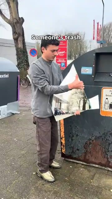 ゴミ箱のそばで写真を持つ男性