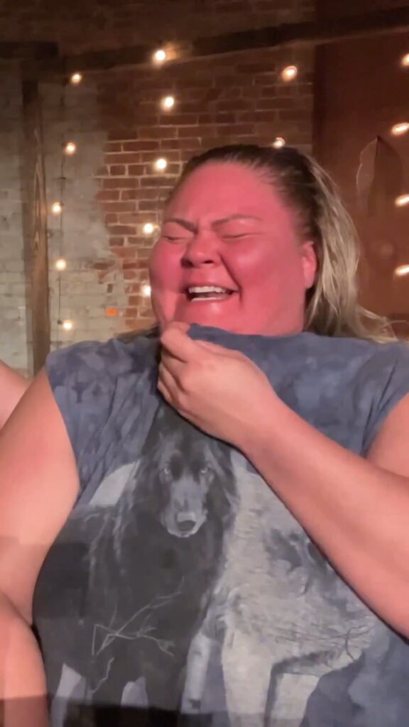 顔を真っ赤にして笑う狼シャツを着た女性