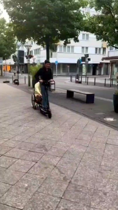 電動キックボードで車椅子を押す人