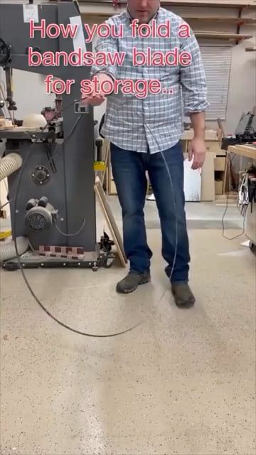 作業場でバンドソーの刃を畳む男性