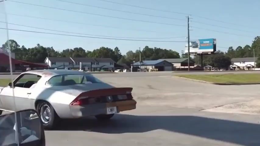 駐車場を走るシルバーのスポーツカー