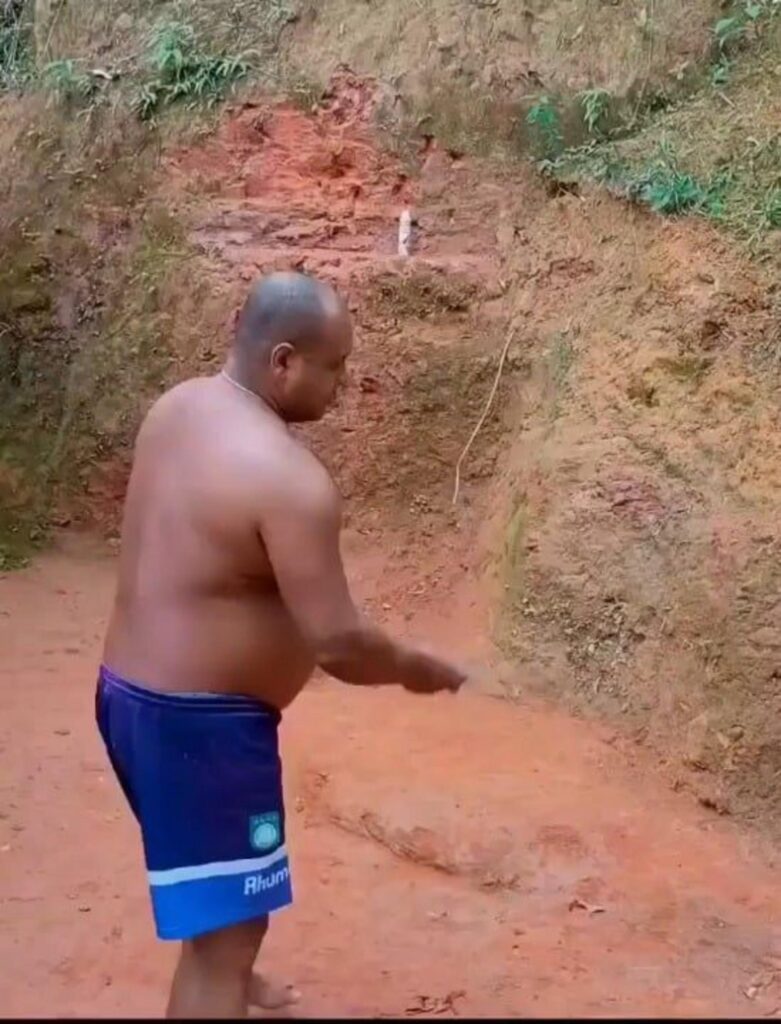 赤土のぬかるみで作業する上半身裸の男性