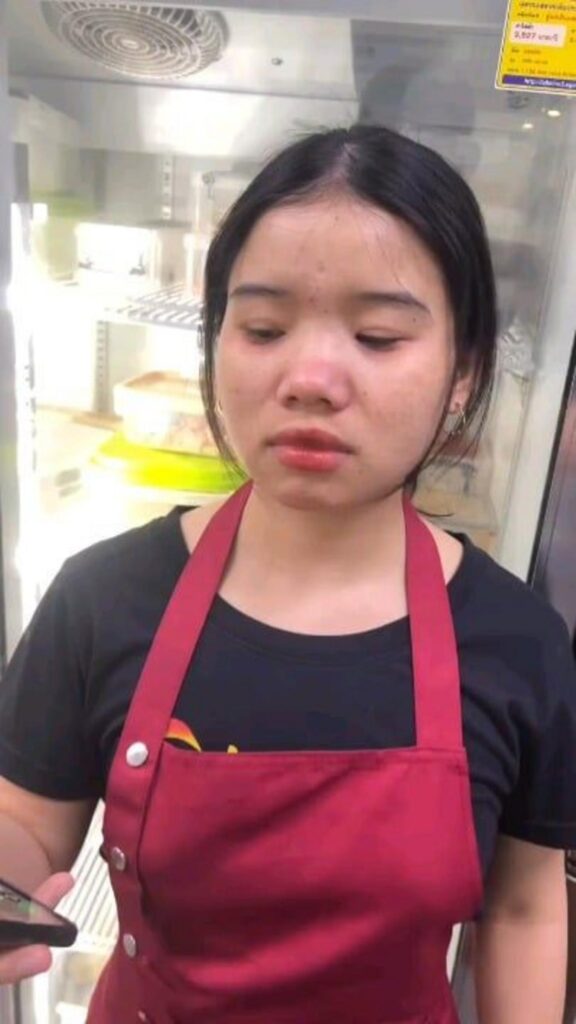 スマホを手に泣きそうな赤いエプロンの女性