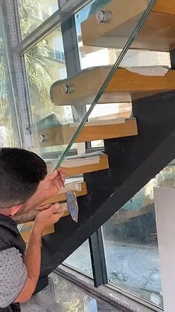 階段のガラス手すりを設置している男性