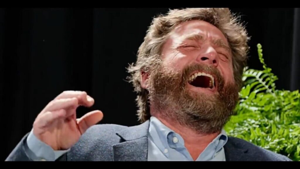 爆笑するスーツ姿のヒゲの男性