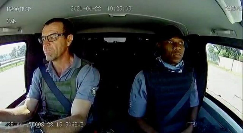 防弾ベストを着て車を運転する男性二人