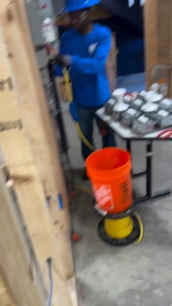 工事現場で作業中の青い服の人とバケツ