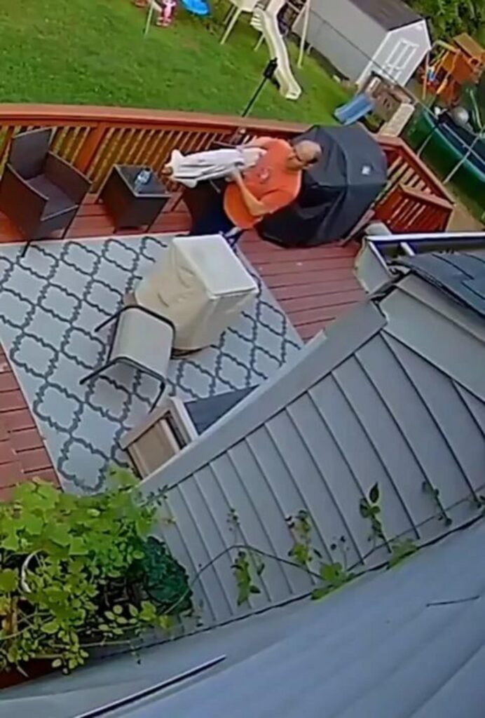 ウッドデッキで白い犬を抱く男性