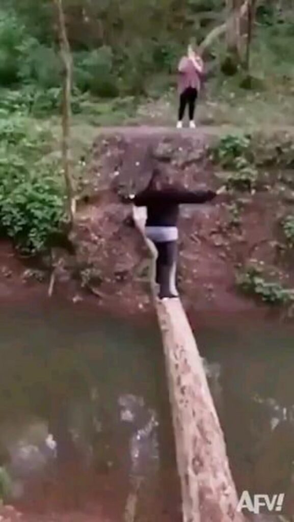 丸太の橋を渡って川を越える人