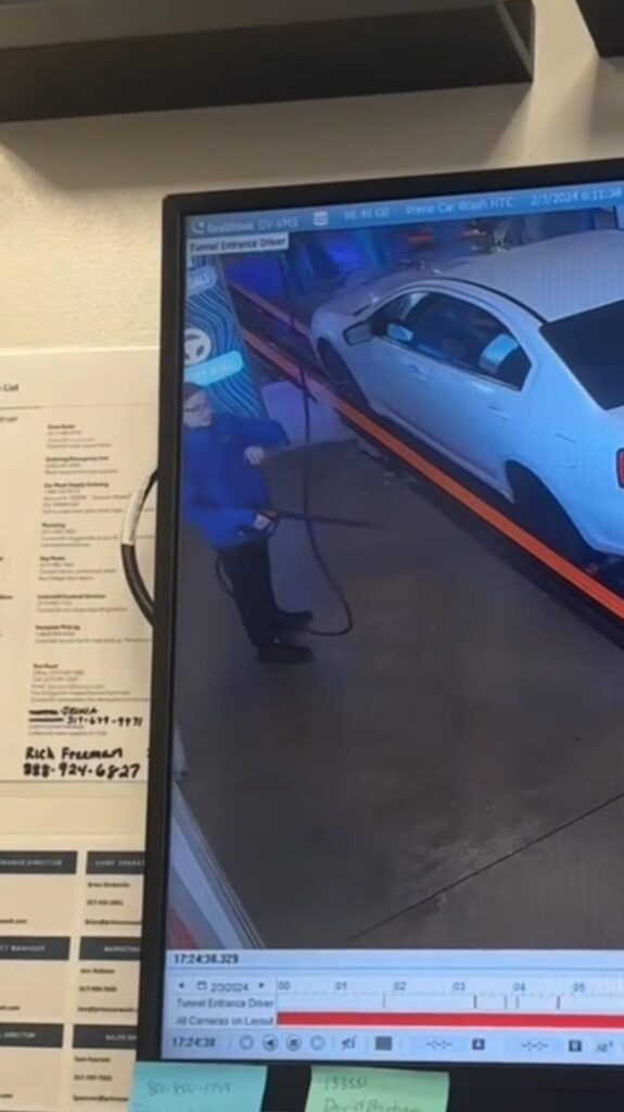 洗車場のモニターに映る作業員と白い車