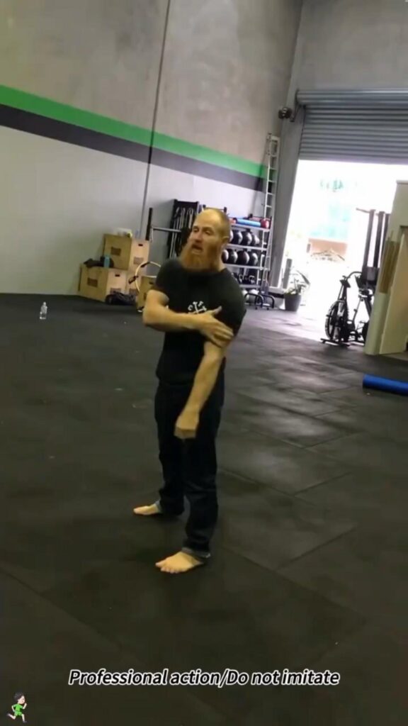 ジムで腕を抑えて立つ赤い髭の男性