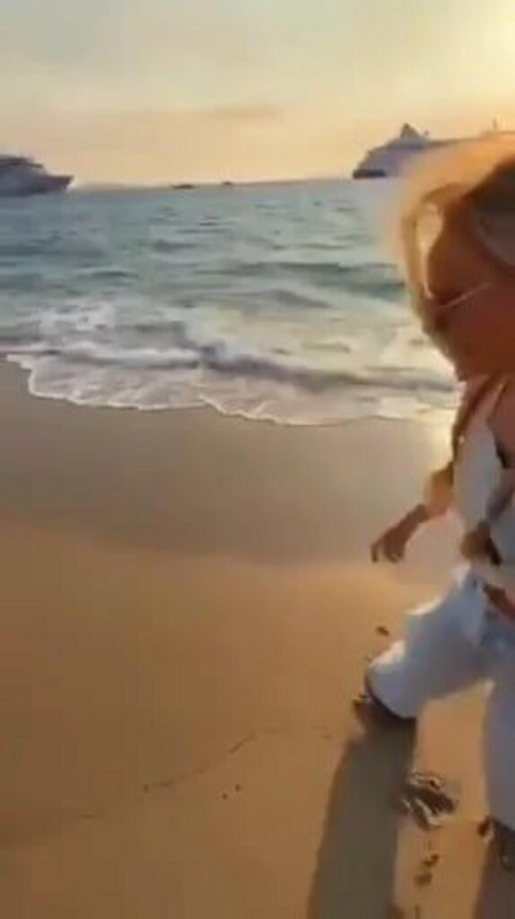 夕暮れの砂浜を歩く女性と豪華客船