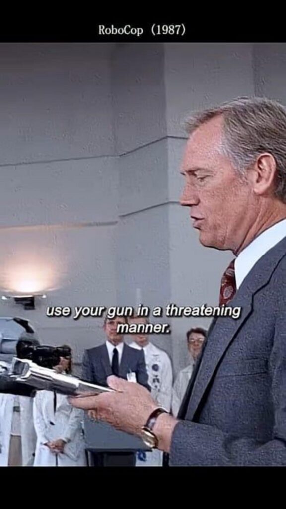 映画ロボコップで銃を構えるスーツの男性