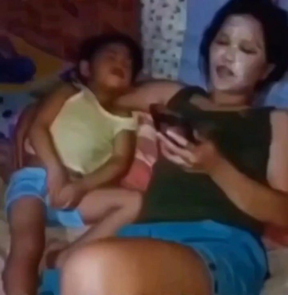 パック姿でスマホを見る女性とその隣の子供