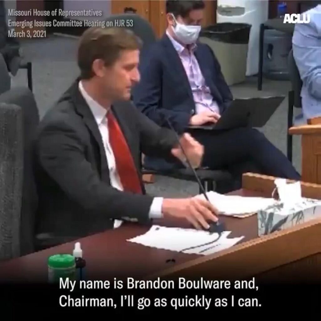 公聴会で発言するスーツ姿の男性