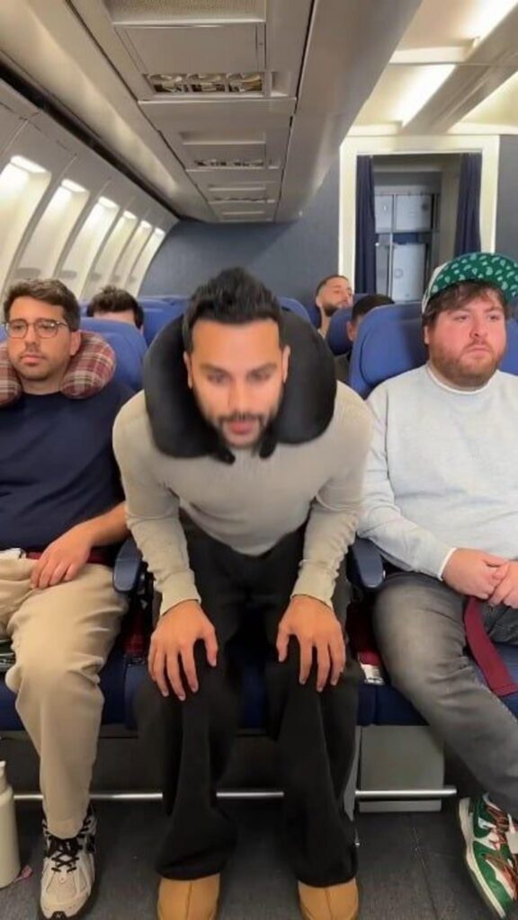 飛行機の座席で首枕を付け屈む男性