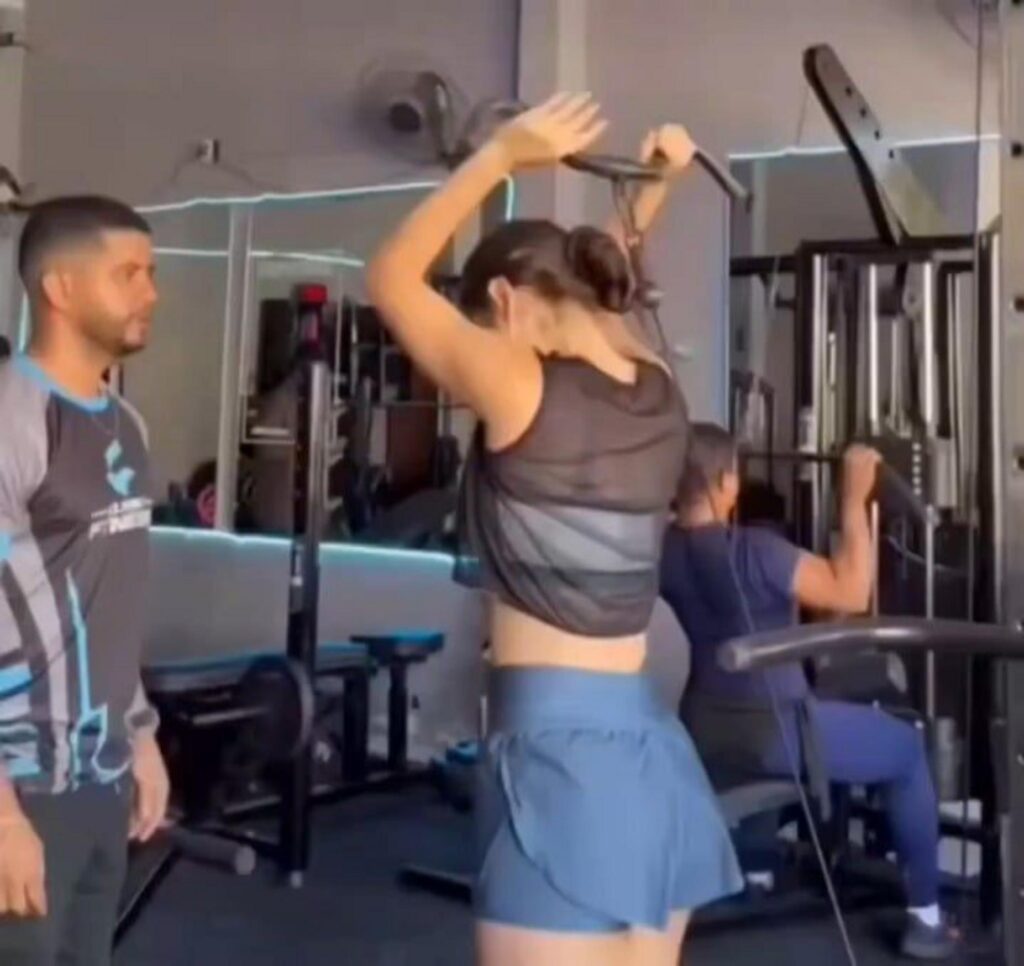 ジムで筋トレをする女性と見守る男性