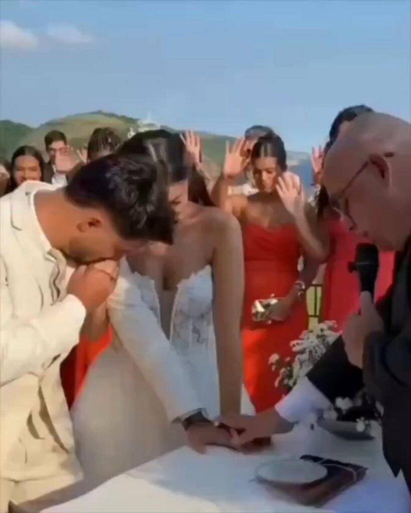 屋外の結婚式で新婦の手にキスをする新郎