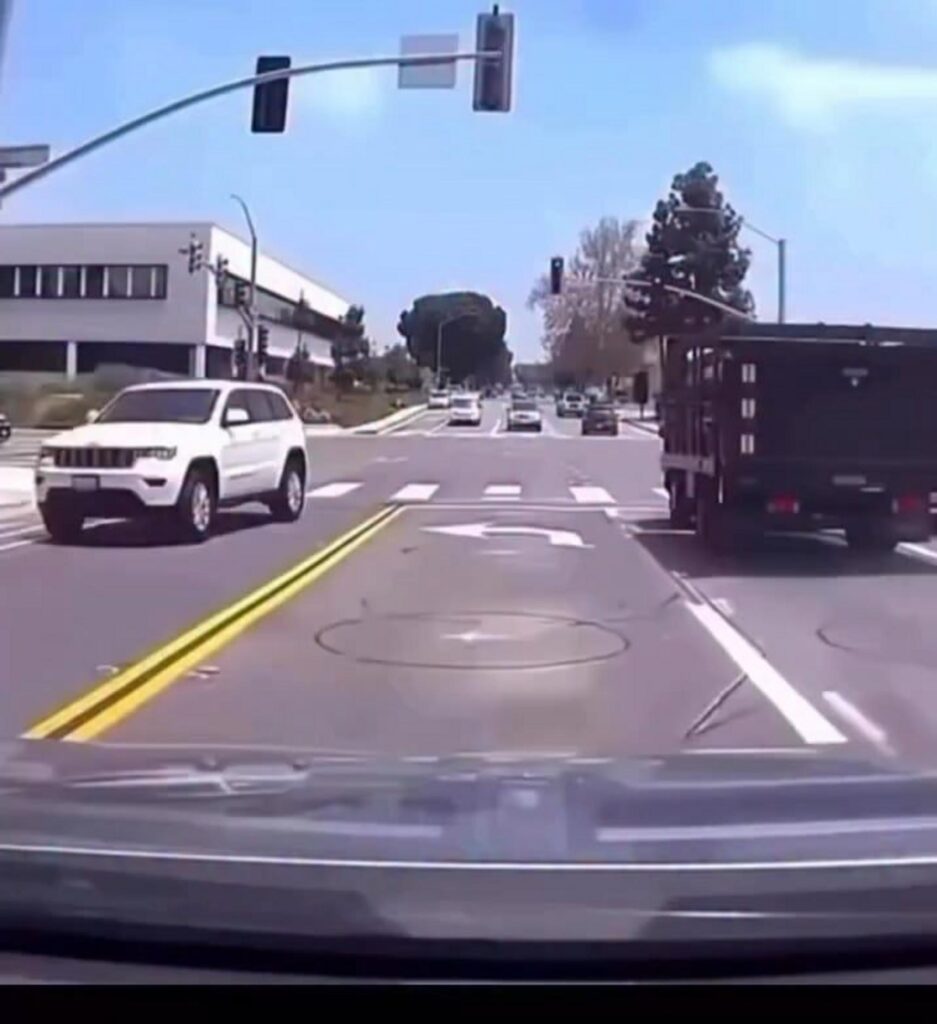 交差点で信号待ちをする車と周囲の風景