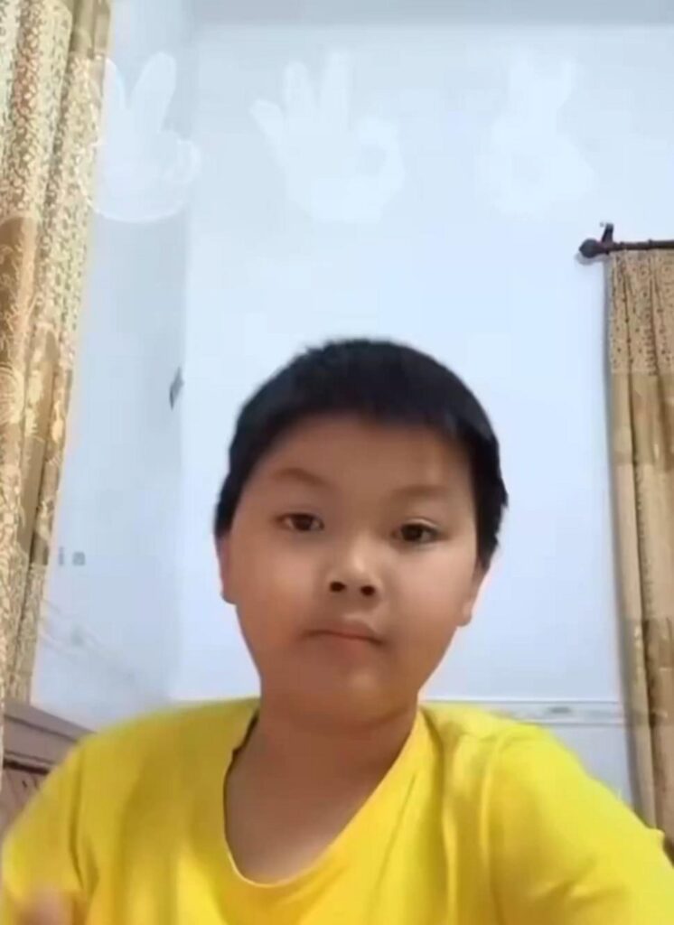 黄色のTシャツを着て正面を見る少年
