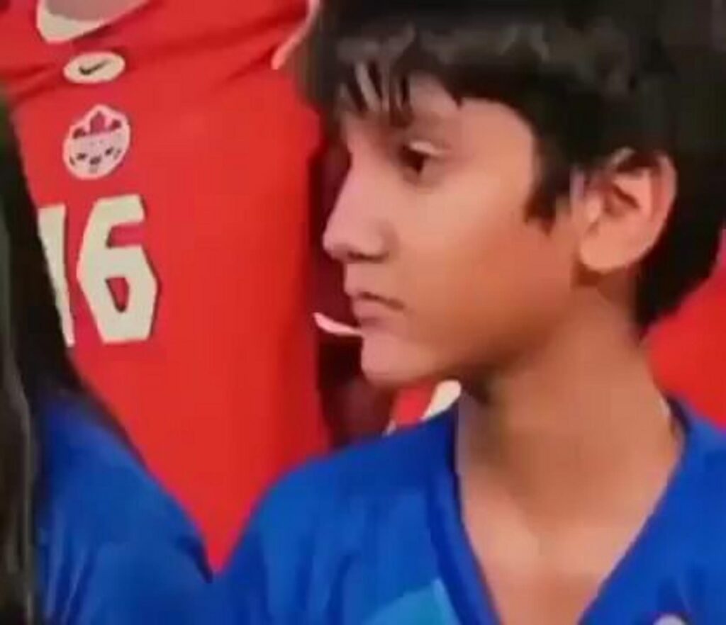 背番号16の隣に立つ青いシャツの少年